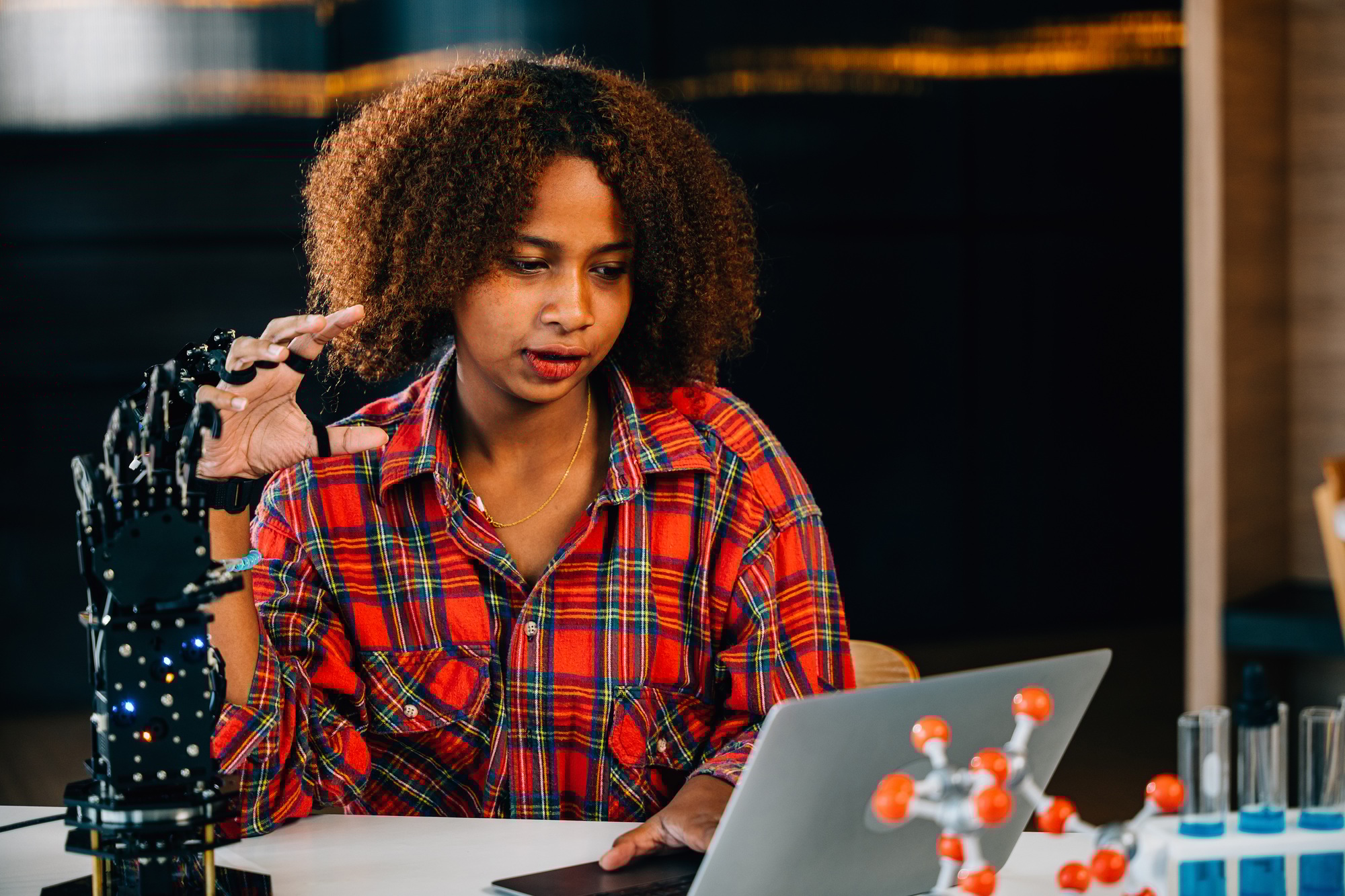Teenage smart whizzkid joyfully experiments with humanoid robotic hand in classroom. Embracing